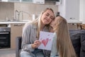 daughter kiss her mom in cheek and gives birthday handmade postcard . mother happy birhday love Royalty Free Stock Photo