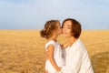 Daughter kisses her mom cheek standing wheat field Royalty Free Stock Photo