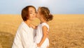 Daughter kisses her mom cheek standing wheat field Royalty Free Stock Photo