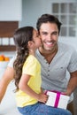 Daughter kissing father holding gift box