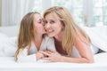 Daughter kissing her mother on the cheek in the bed Royalty Free Stock Photo