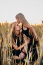 Daughter kissing her mum. Happy family together on sunset in summer golden wheat field. Royalty Free Stock Photo