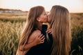 Daughter kissing her mum. Happy family together on sunset in summer golden wheat field Royalty Free Stock Photo