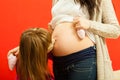 Daughter kissing her pregnant mother belly Royalty Free Stock Photo