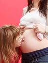 Daughter kissing her pregnant mother belly Royalty Free Stock Photo