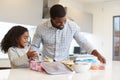 Daughter In Kitchen At Home Helping Father To Make Healthy Packed Lunch