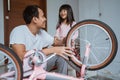 Daughter laughs happily as her father fixes his little bike