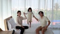 Daughter is leaping on the bed for fun. With father and mother to take care