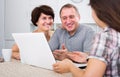 Daughter learning her elderly parents working on laptop