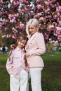 A daughter lies on her mother's chest under a cherry blossom on a sunny spring day