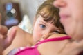 The daughter lies on the shoulder of her mother. Portrait of a little girl with beautiful eyes. Serious look of a small child.