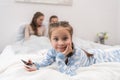 Daughter lying on a bed with smartphone parents sitting Royalty Free Stock Photo