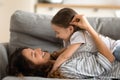 Daughter and mother lying on couch enjoy moment of tenderness