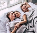 The daughter and parents sleeping under the blanket.