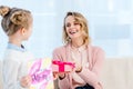 daughter presenting gift box to laughing mother at home on happy Royalty Free Stock Photo