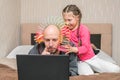 The daughter puts the slinky toy to the father`s head. Family is quarantined at home. A little girl is making fun of dad. A child Royalty Free Stock Photo