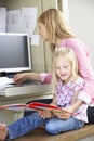 Daughter Reading Book Whilst Mother Works In Home Office Royalty Free Stock Photo