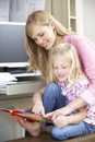 Daughter Reading Book Whilst Mother Works In Home Office Royalty Free Stock Photo