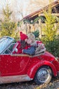Daughter in red coat and hat kisses father in Santa`s car under flying snow