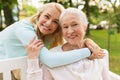 Daughter with senior mother hugging on park bench Royalty Free Stock Photo
