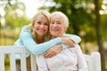 Daughter with senior mother hugging on park bench