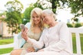 Daughter and senior mother with smartphone at park Royalty Free Stock Photo