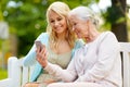 Daughter and senior mother with smartphone at park Royalty Free Stock Photo