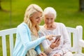 Daughter and senior mother with smartphone at park Royalty Free Stock Photo