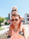 The daughter sits on dad& x27;s shoulders. Daddy carries a small child around his neck. Summer vacation concept near the sea Royalty Free Stock Photo