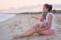 happy modern mother and girl child on seashore in the evening having fun time. Happy family relaxing resting at beach in Royalty Free Stock Photo