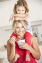 Daughter Sitting On Shoulders Whilst Mother Eats Yoghurt Royalty Free Stock Photo