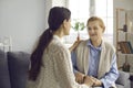 Daughter talking to happy senior mother and holding her hand sitting on sofa at home Royalty Free Stock Photo