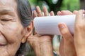 Daughter talking to hearing impaired elderly woman , using paper tube