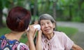Daughter talking to hearing impaired elderly woman , using paper tube