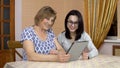 Daughter teaches mother how to use a tablet. A young woman shows her old mother where to click on a tablet. The family Royalty Free Stock Photo