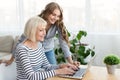 Daughter teaching mother to use laptop at home