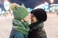 Daughter teenager gently kisses his mother in the nose while standing on a nightly brightly lit street in winter Royalty Free Stock Photo