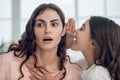 Daughter telling secret to mother in whisper in ear