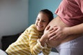 Daughter touching the belly of her pregnant mother Royalty Free Stock Photo