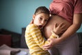 Daughter touching the belly of her pregnant mother. Royalty Free Stock Photo