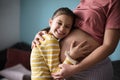 Daughter touching the belly of her pregnant mother Royalty Free Stock Photo