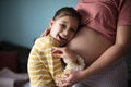 Daughter touching the belly of her pregnant mother Royalty Free Stock Photo