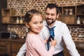 daughter tying up necktie for father in morning and looking