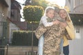 Daughter and wife hugging soldier in Ukrainian military uniform outdoors, space for text. Family reunion