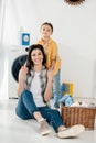 daughter in yellow shirt holding mother sitting on floor near basket Royalty Free Stock Photo