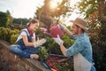 Daugther and father working together in the flower garden outdoors, girl holding a flower pot, man watering it with watercan