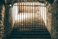 A daunting staircase leading to a passage blocked by an iron grid in a medieval dungeon