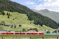 A red passenger express train is crossing along the beautiful Davos lake