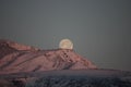 At dawn, a beautiful full moon peeps out over the hill. Full moon at dawn. Moonrise among the alpine peaks. Full moon before