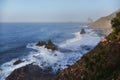 Dawn breaks over a tranquil coast with rocky cliffs and undulating waves, creating a peaceful seascape